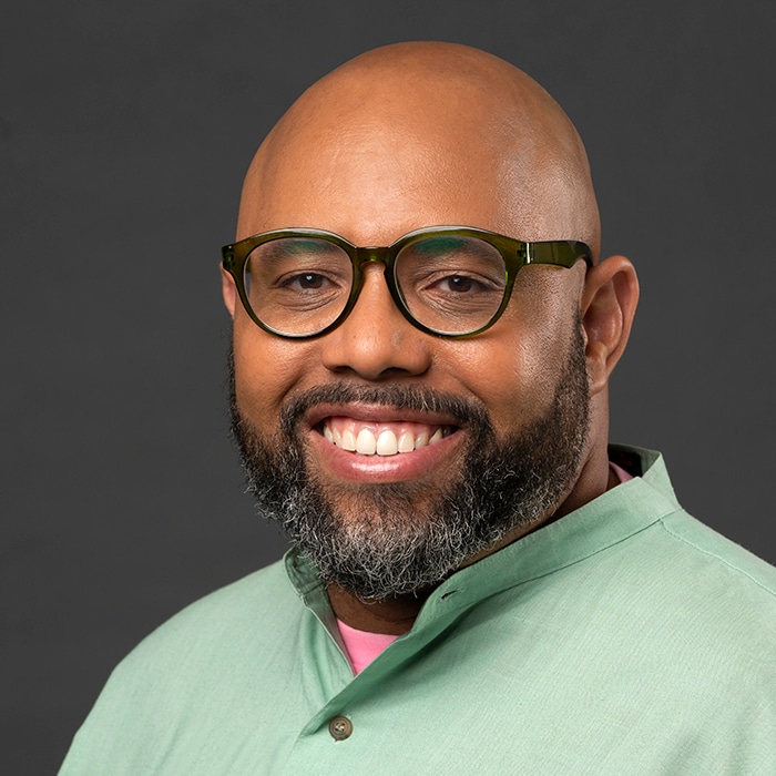 Anthony-Q.-Farrell - a person in a green shirt wearing glasses