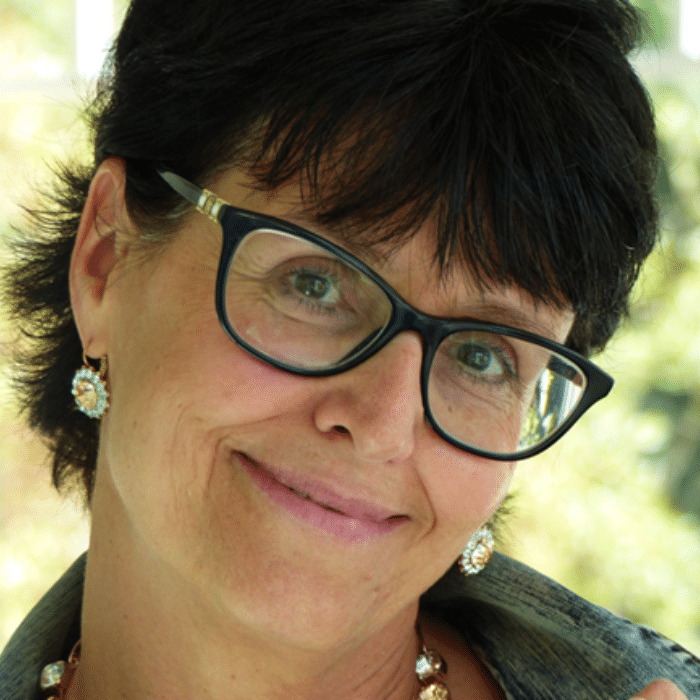Connie Edwards wearing glasses with short dark hair and earrings.