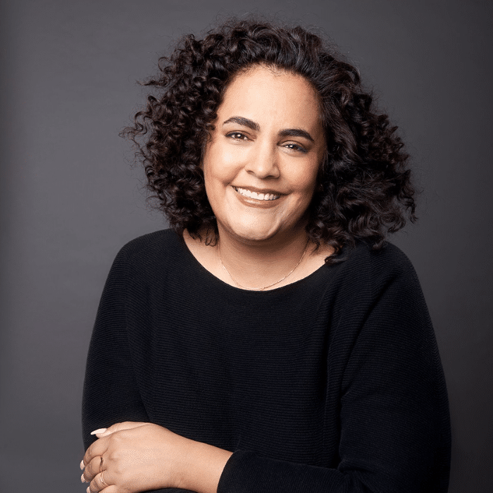 Tamara Dawit with curly hair, black long-sleeved shirt against a grey background
